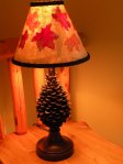 An image of a lamp shade with oak leafs and the lamp is on.